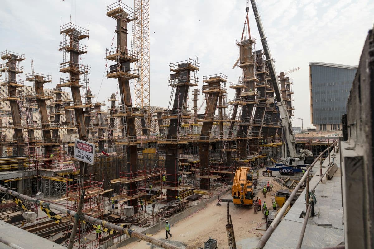 Bustling construction site with towering steel frameworks and cranes under a cloudy sky