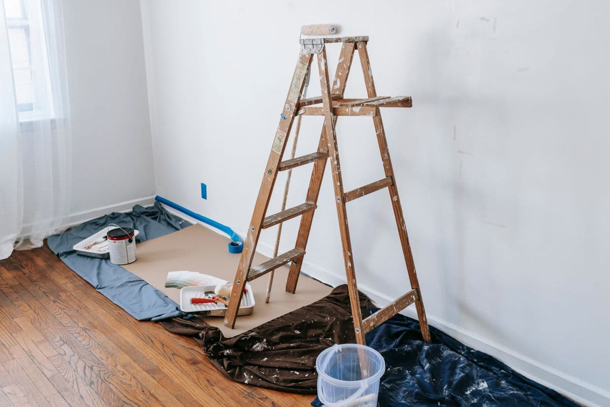 Wooden stepladder set up inside a room with painting tools nearby