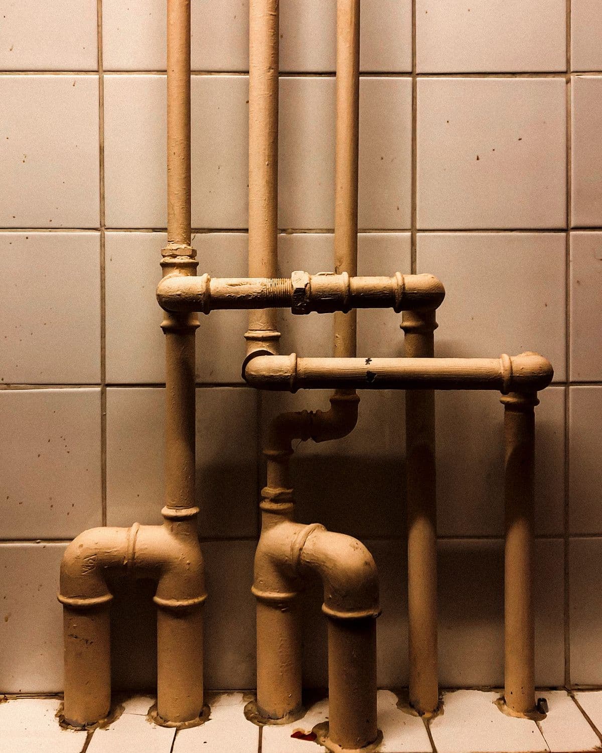 Vertical industrial pipes against a tiled wall showcasing installation detail