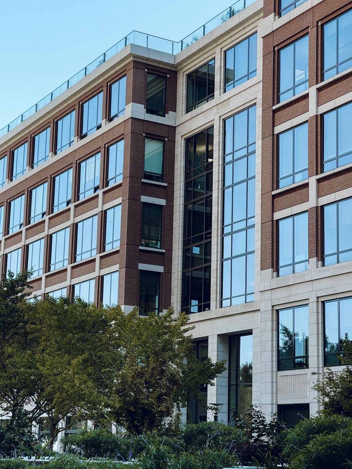 Contemporary office building exterior featuring large glass windows and green surroundings