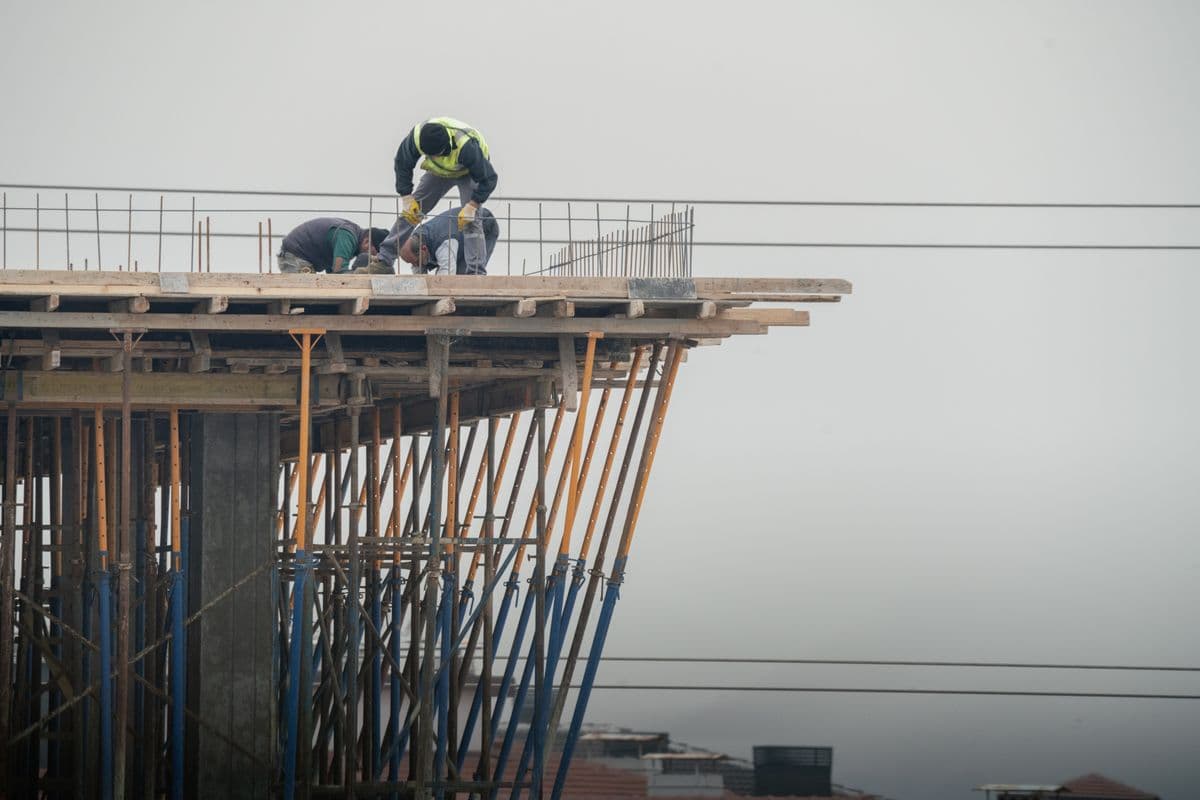 Construction workers in hard hats pouring concrete on a high-rise building site